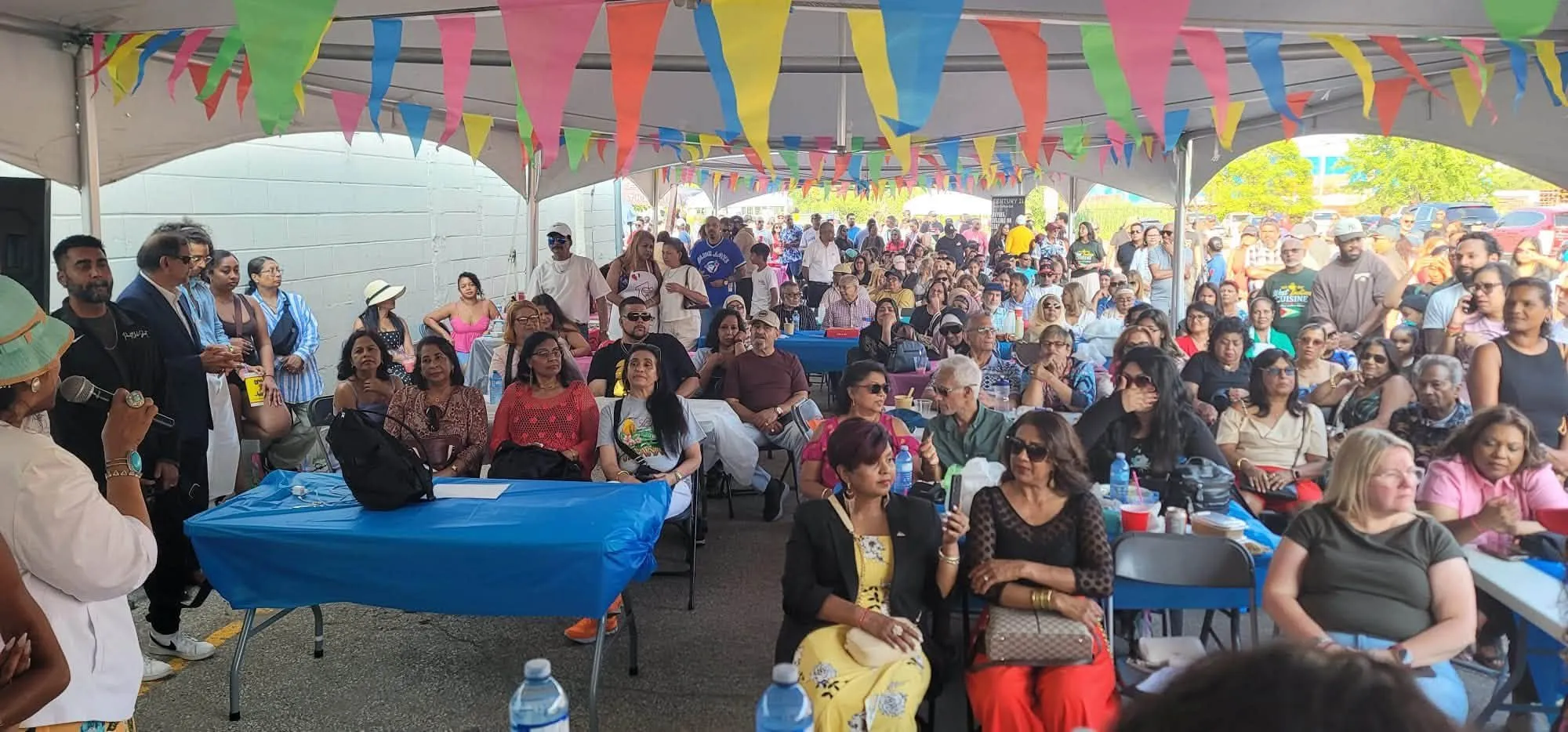 A packed tent of guests seated under colourful bunting at the One Love Duck Curry Festival