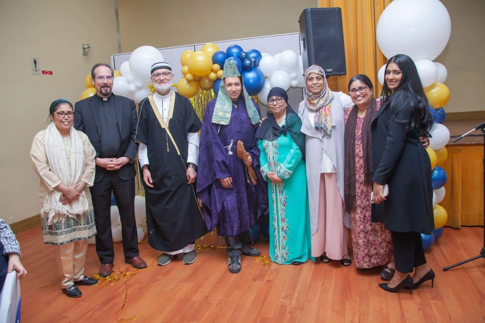 Faith leaders and guests posing together in front of balloons at the gala