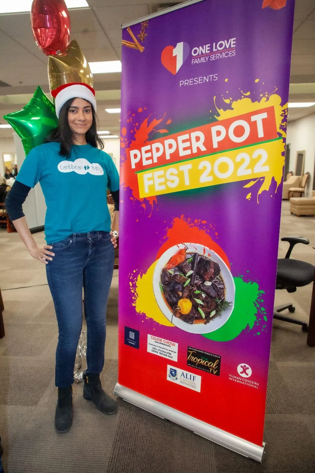 A volunteer standing beside the Pepperpot Fest 2022 banner