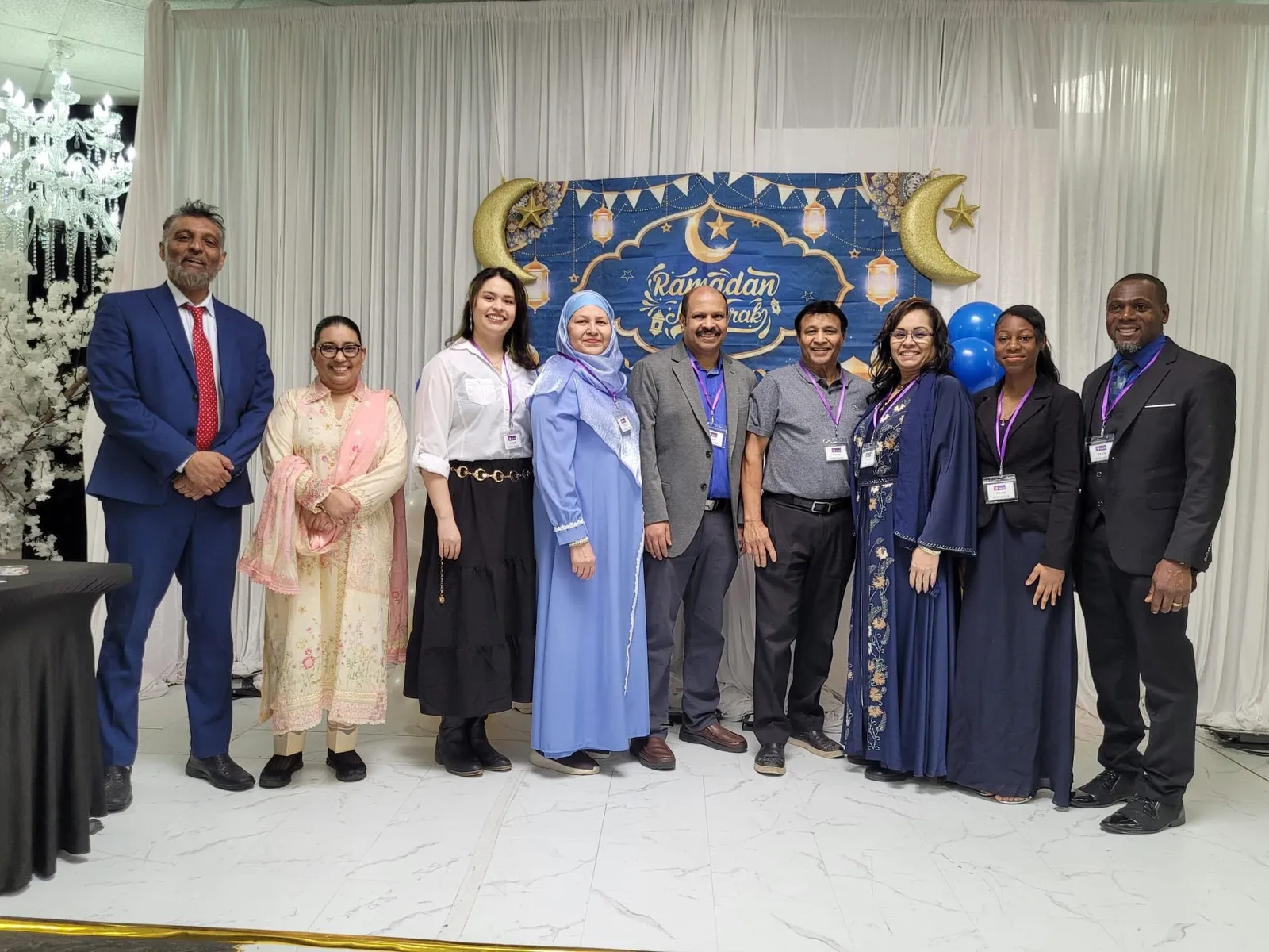 Guests of many faiths standing together in front of a Ramadan Mubarak backdrop