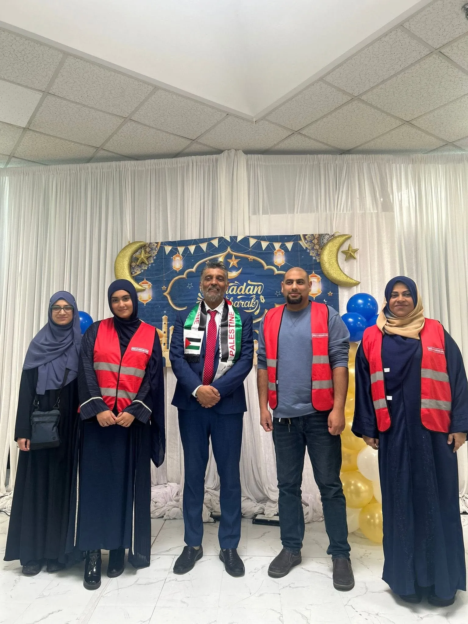 Volunteers in red vests with Habeeb Alli at the Ramadan interfaith dinner
