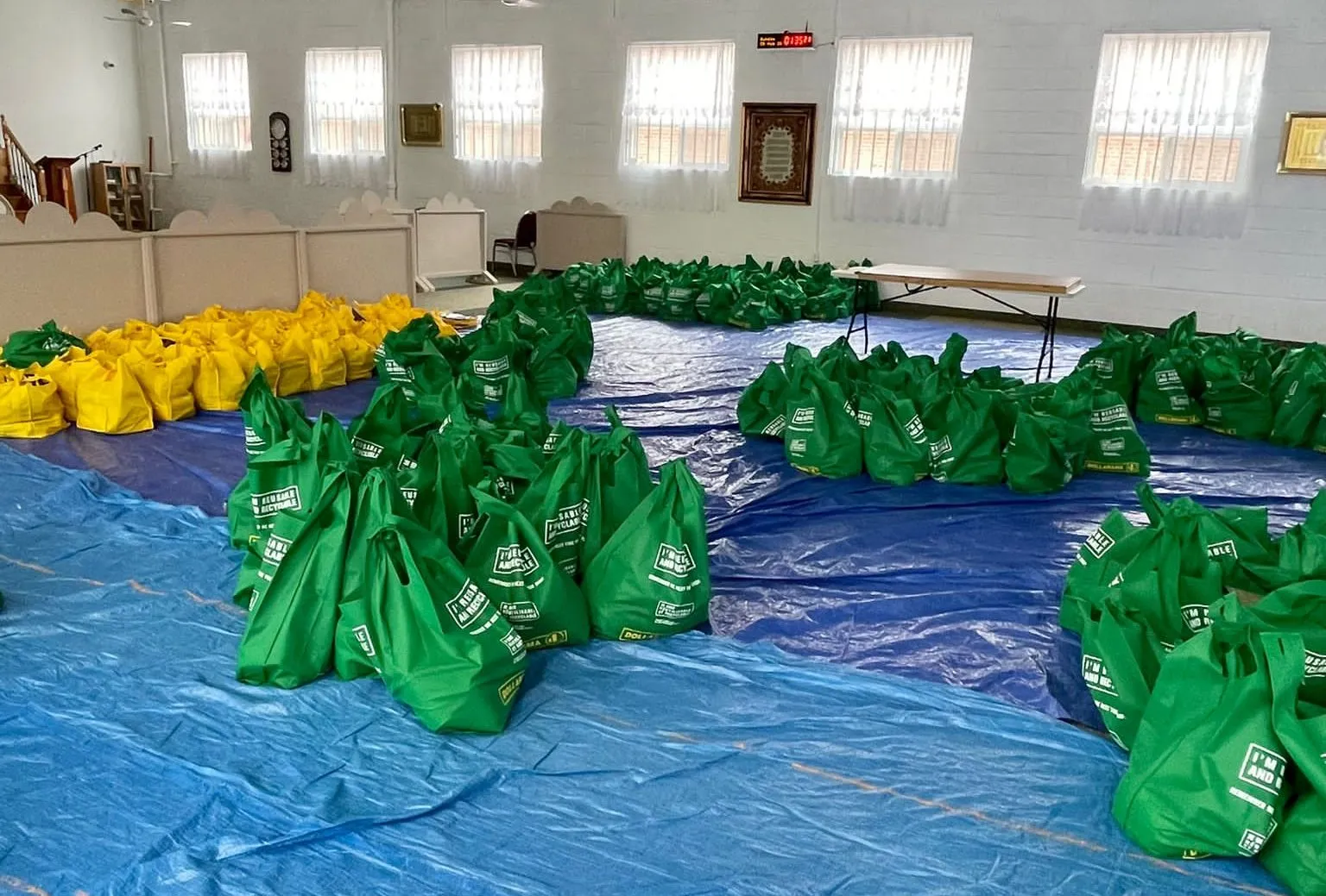 Rows of packed hamper bags laid out in a community hall, ready for distribution